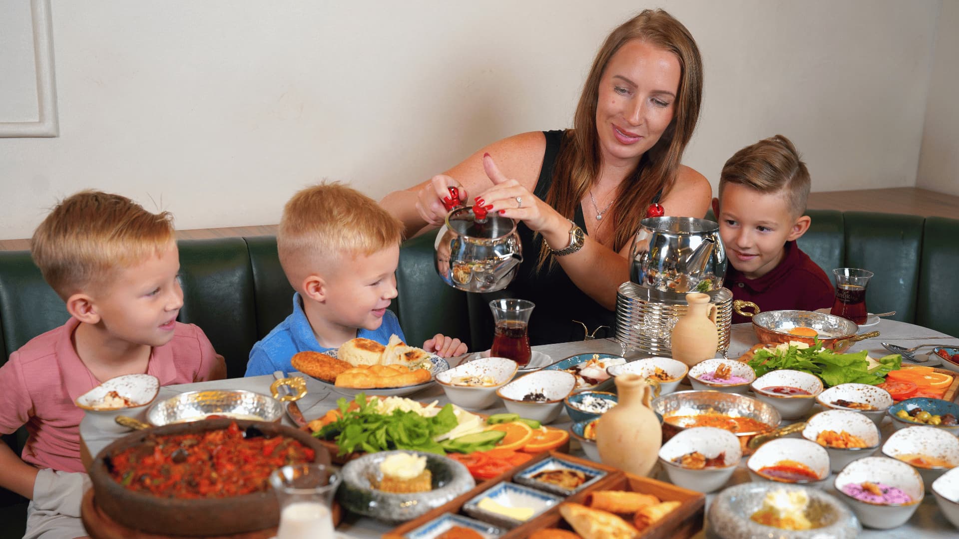 A woman having foo with three kids and lots of food on the table